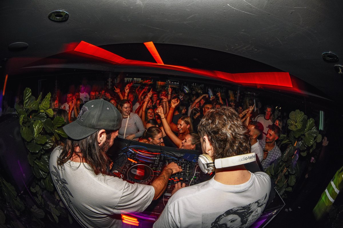 DJ playing to a full room at Pelicano, red light and haze